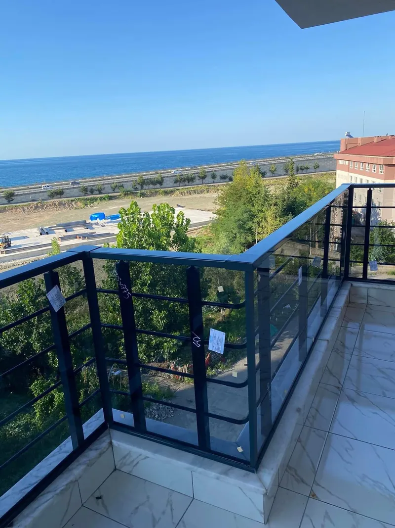 Antrasit profilli füme camlı korkuluk, deniz manzaralı geniş terasın iki kenarını köşe yaparak sarıyor